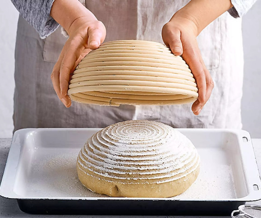 Brotlaib wird aus dem Gärkorb auf ein Backblech gestürzt.