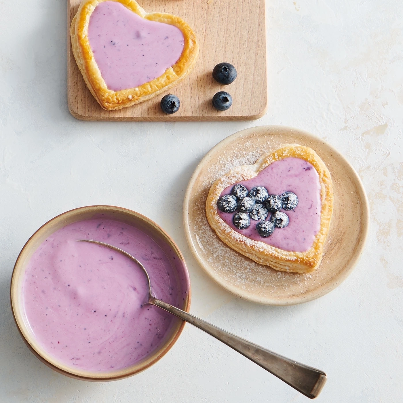 Herzförmige Gebäckstücke mit Blaubeeren und Creme, auf einem Tisch