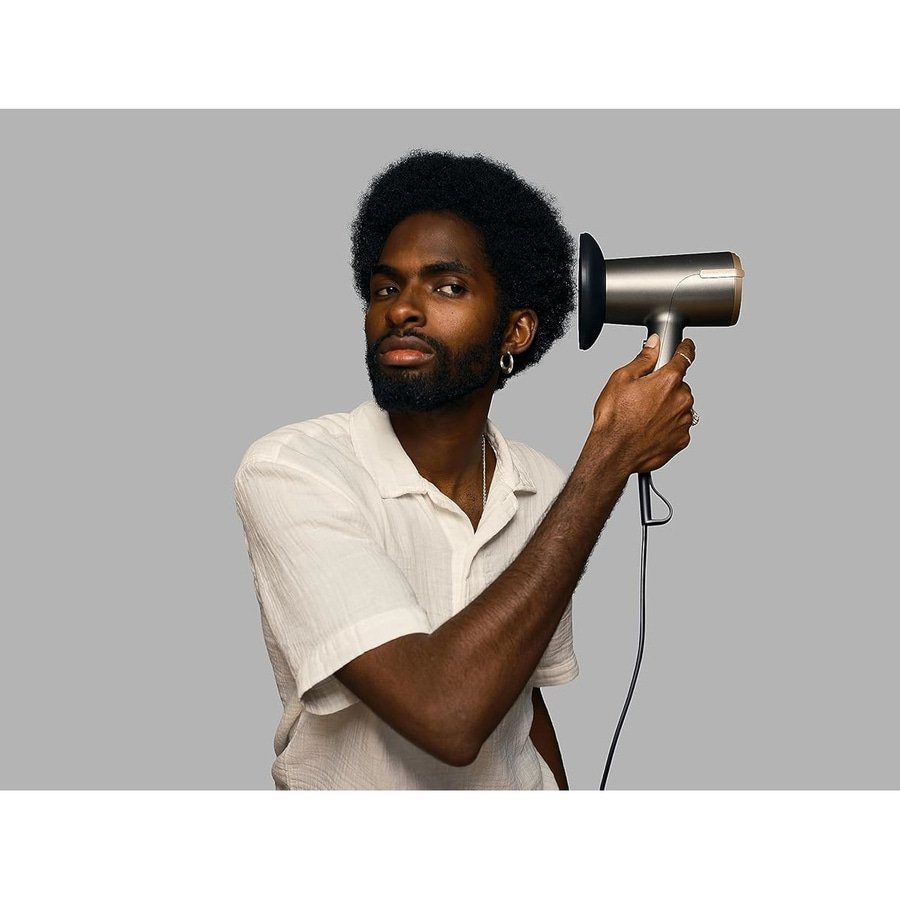 Mann mit Afrohaaren hält einen silbernen Haartrockner