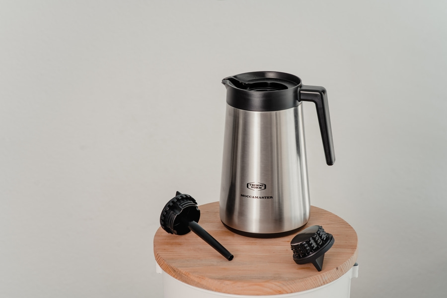 Kaffeekanne mit Deckel und Filtern auf einem Holzbrett, isoliert