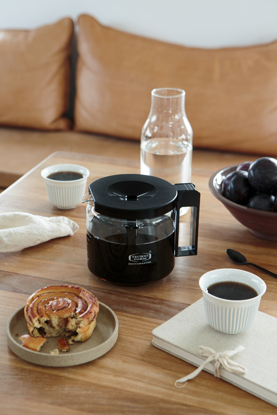 Kaffeemaschine, Kaffee, Gebäck, Obst, Notizbuch auf einem Holztisch