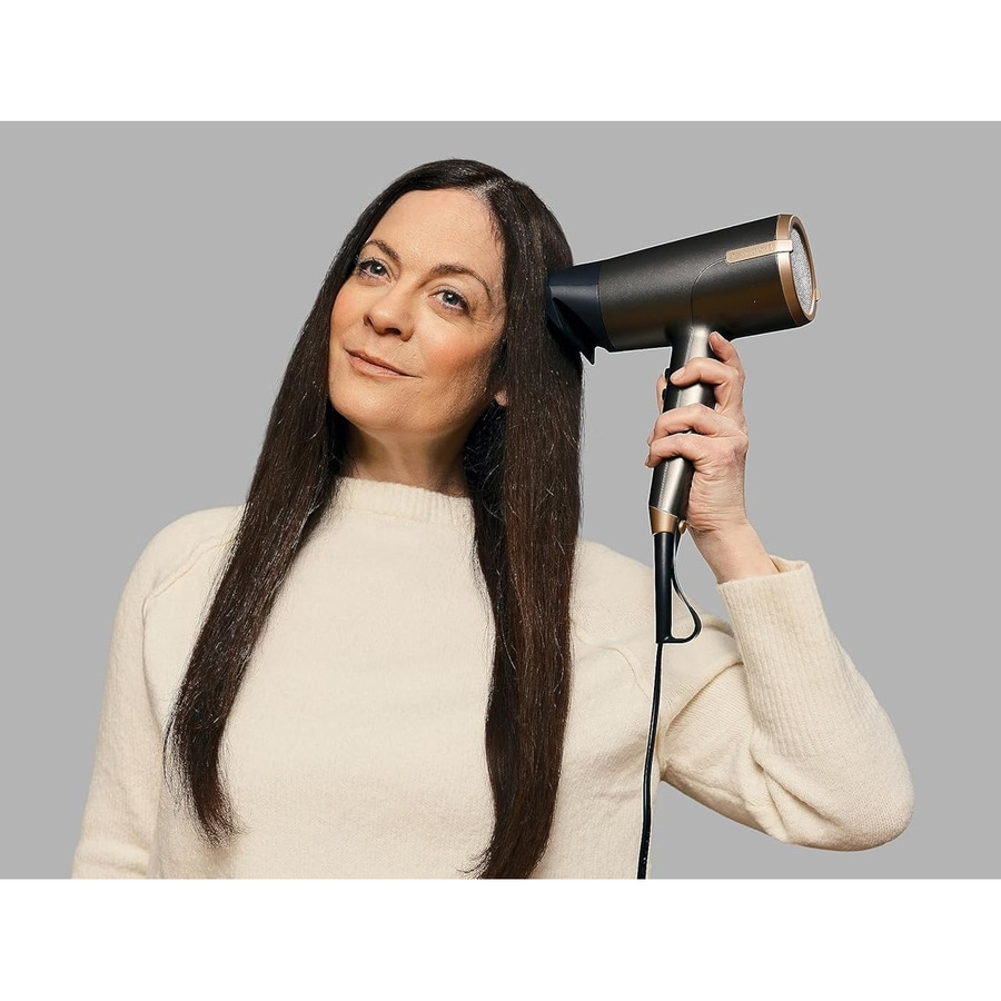Frau föhnt ihr langes braunes Haar mit einem dunklen Föhn.