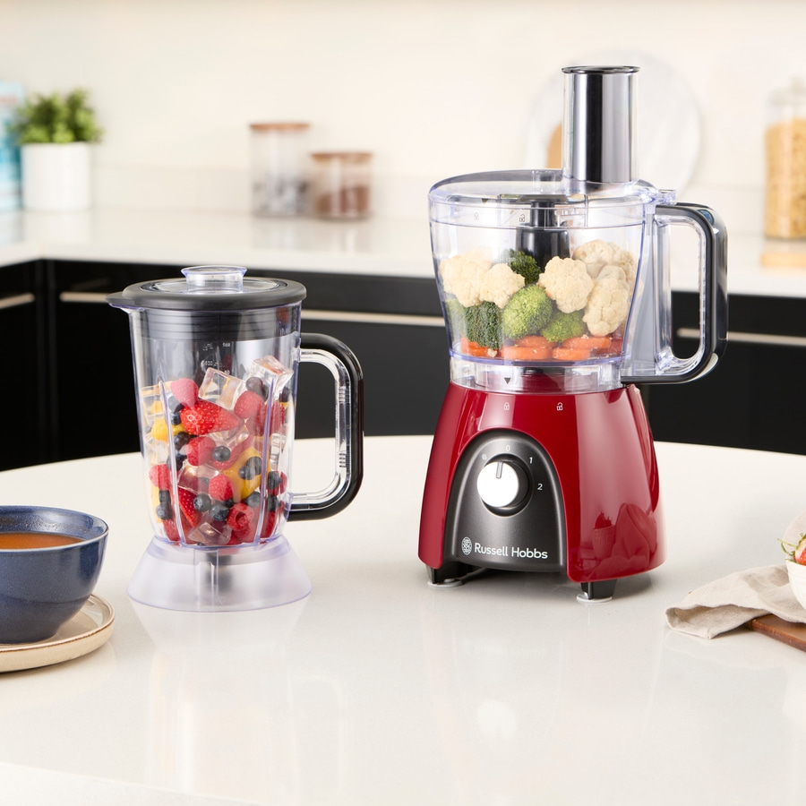 Küchenszene mit einem Mixer und einem Food Processor auf einer weißen Oberfläche.