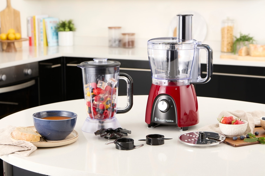 Küchengeräte: Mixer und Küchenmaschine mit Obst und Gemüse auf dem Tisch.