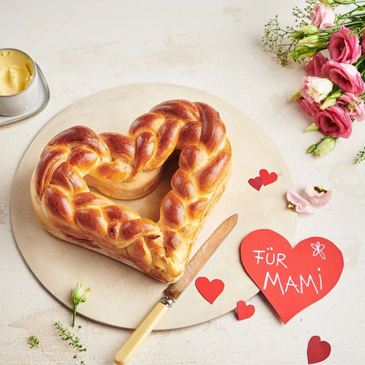 Herzförmiges Brot, Blumen, Butter, Messer, Herz-Karte mit Text 'Für Mami'
