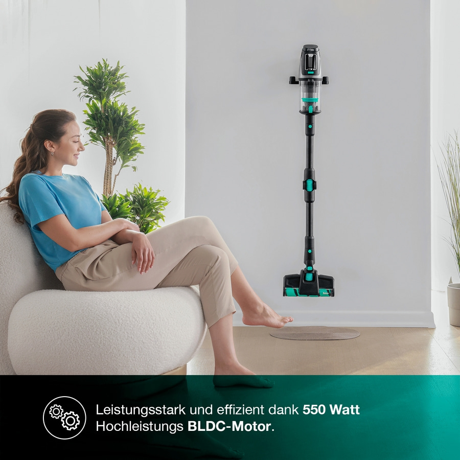 Eine Frau sitzt auf einem Sofa, während ein Staubsauger an der Wand hängt.