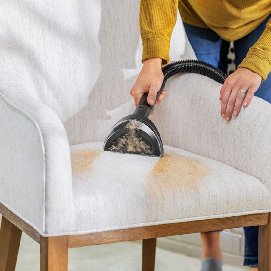 Person reinigt Stuhl mit Staubsauger, Flecken auf dem Sitz, Nahaufnahme