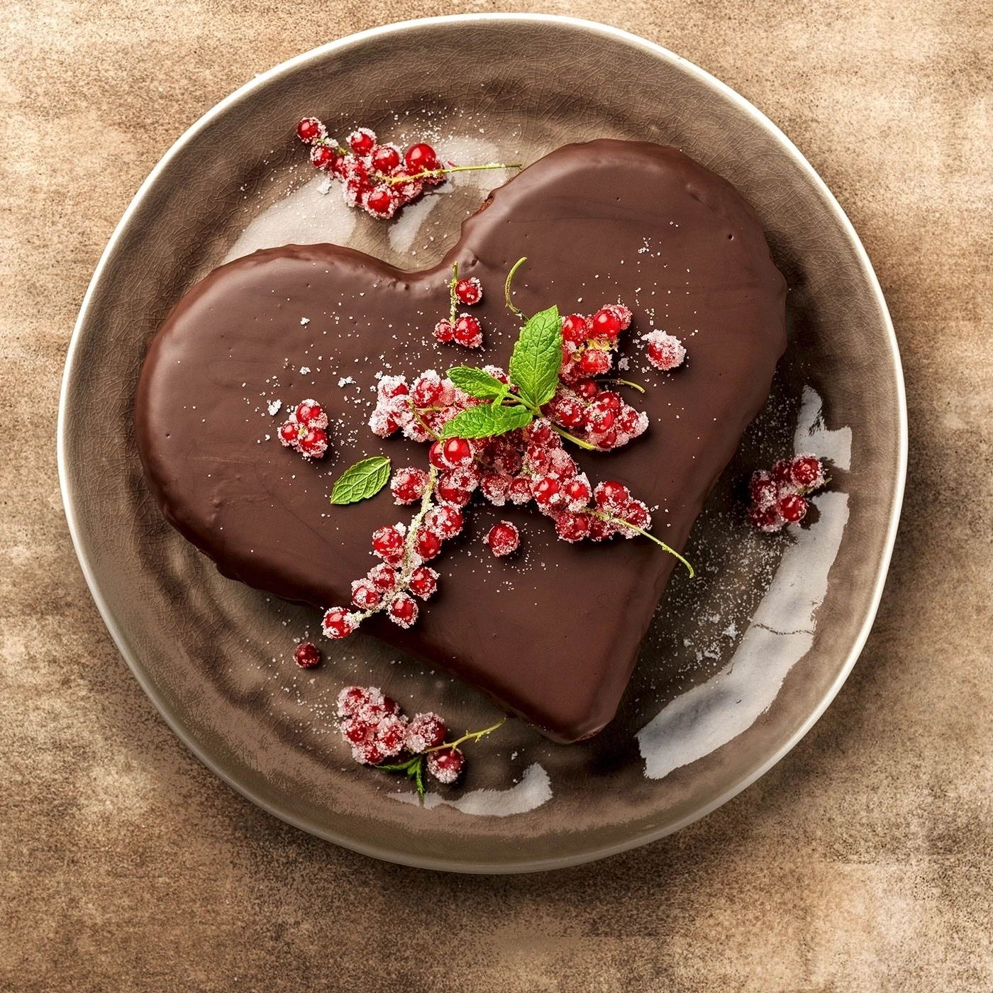 Herzförmiger Schokoladenkuchen mit roten Beeren auf einem Teller, Nahaufnahme