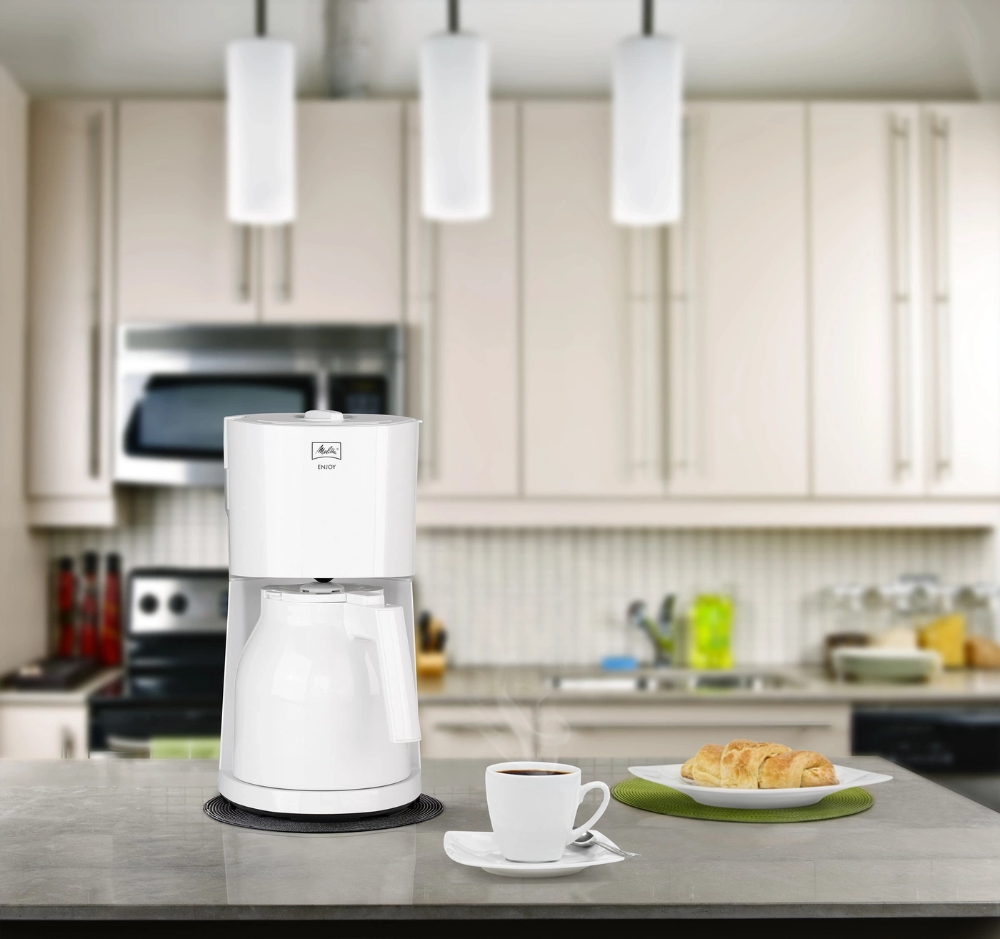 Kaffeemaschine, Tasse, Croissant auf dem Tisch in der Küche, Frühstück