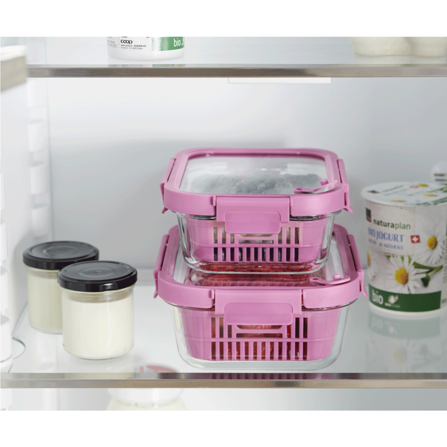 Kühlschrank mit rosa Behältern, Gläsern und Joghurt. Lebensmittelaufbewahrung.