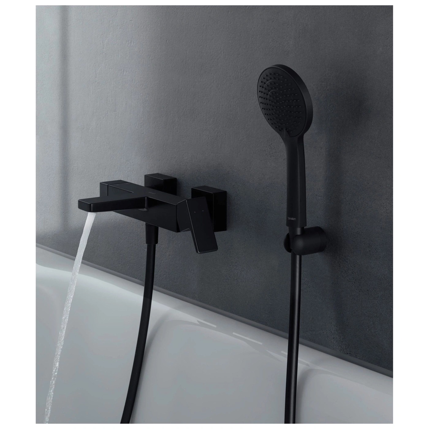 Schwarze Badarmatur mit Wasserstrahl und Dusche vor grauer Wand