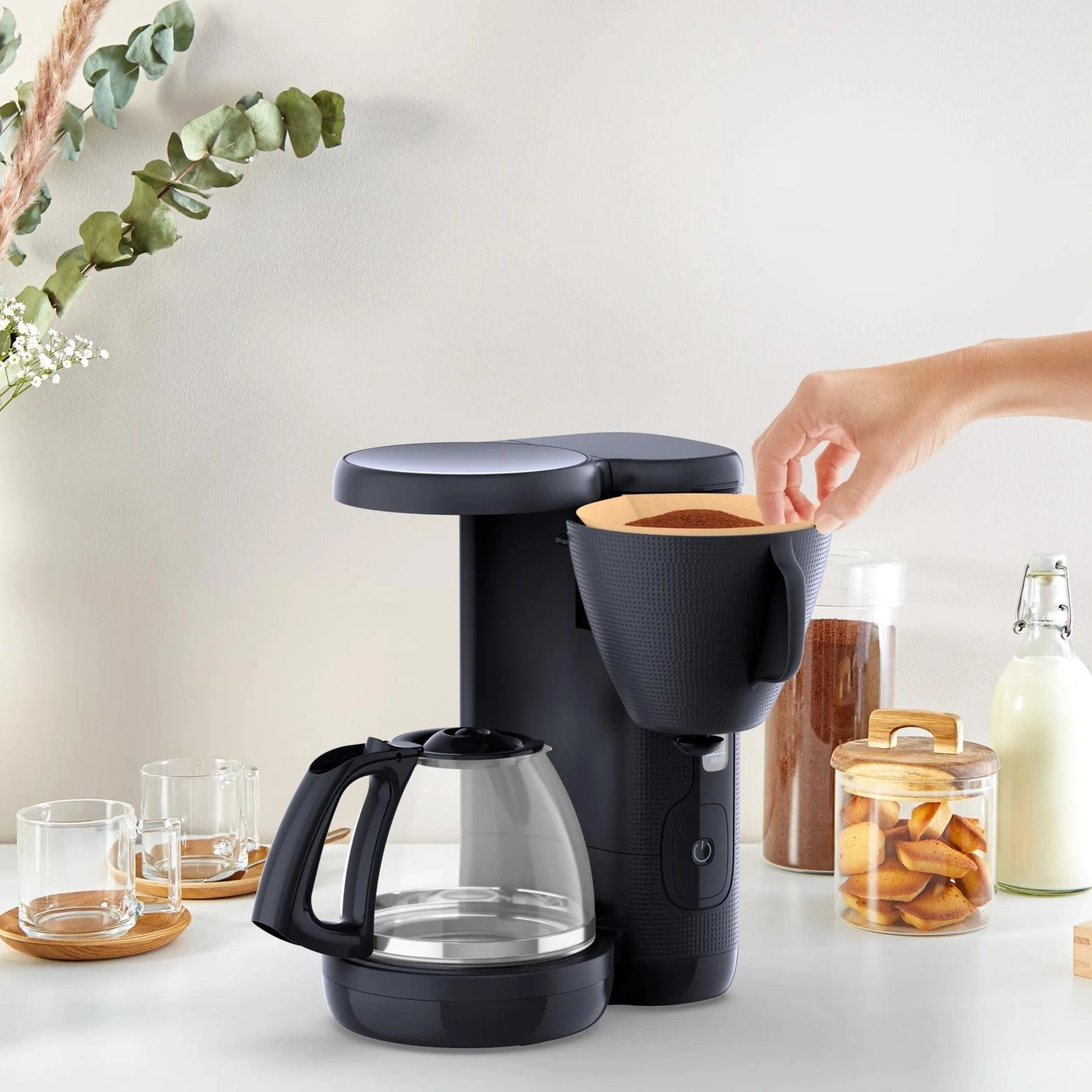 Kaffeemaschine mit Kaffeefilter und Glaskanne auf dem Tisch.