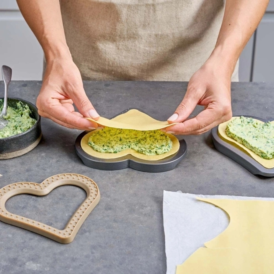 Person macht Herz-Ravioli. Teig, Füllung, Formen. Nahaufnahme. Kochen.