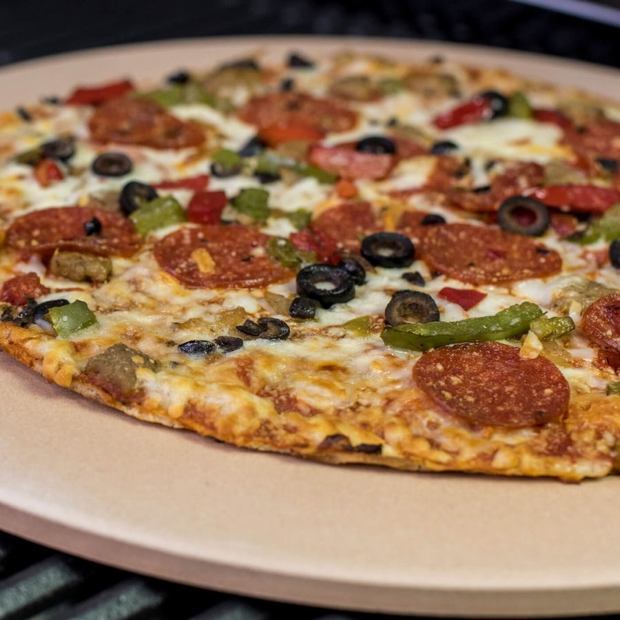 Pizza mit Salami, Oliven, Paprika und Käse auf einem Pizzastein