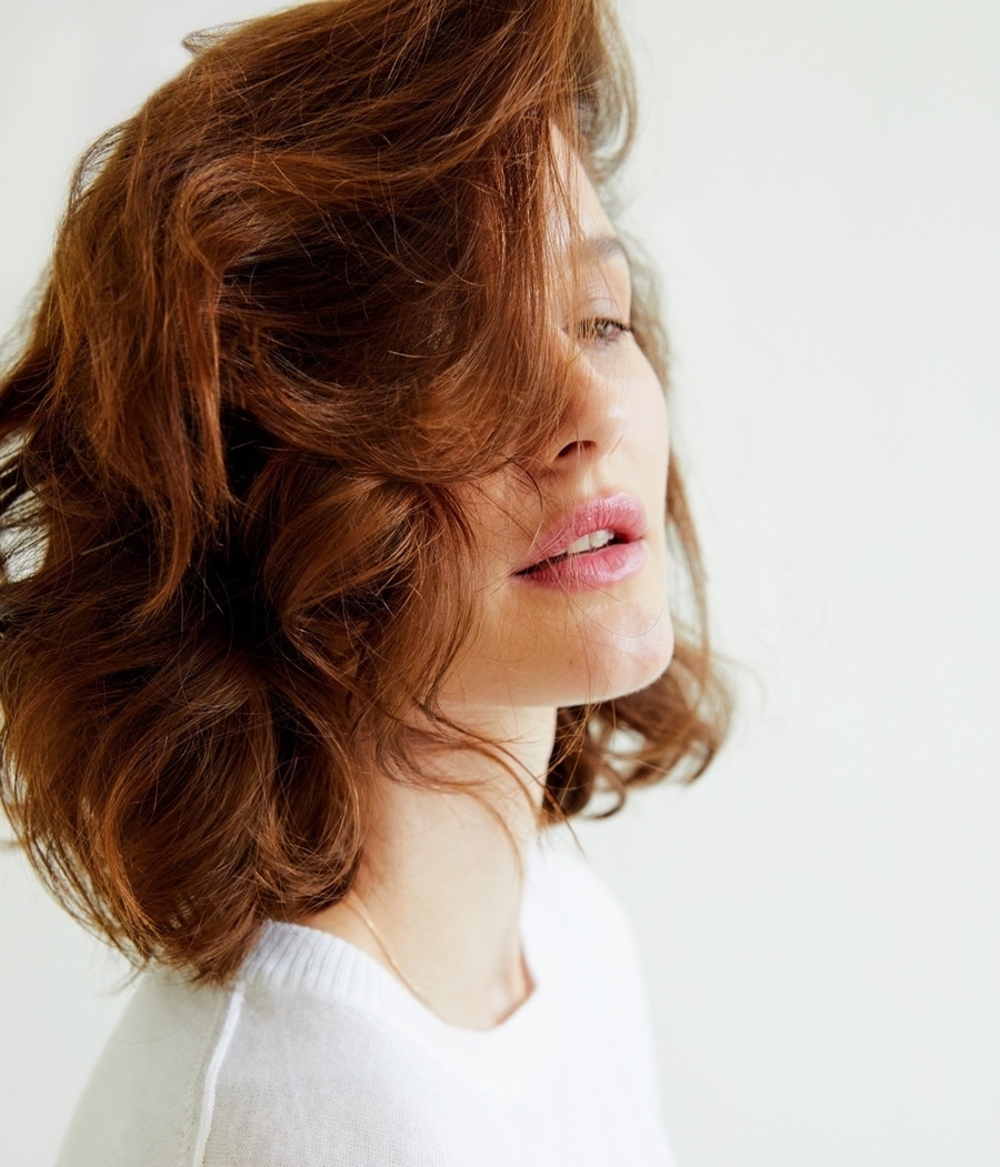 Porträt einer Frau mit roten Haaren und rosa Lippen, die in die Kamera schaut