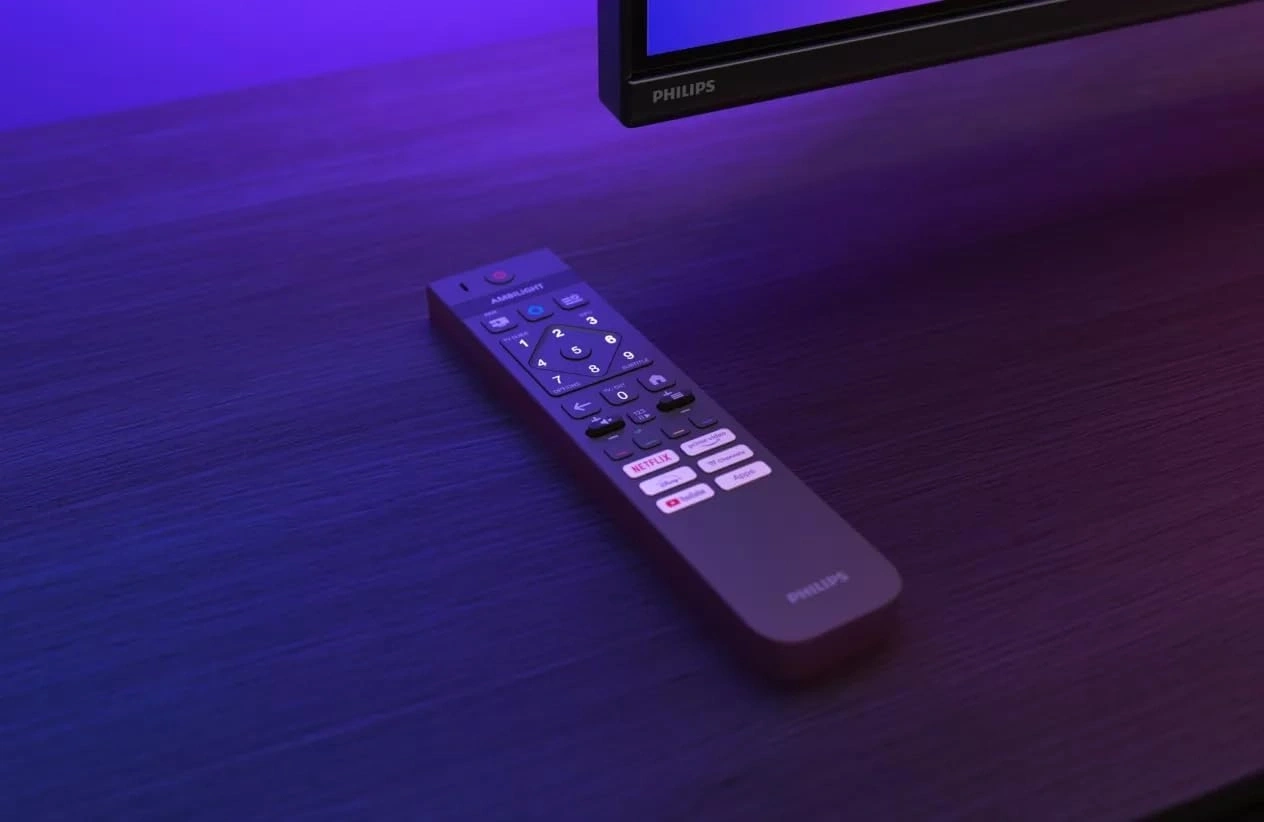 Eine Philips TV-Fernbedienung liegt auf einem dunklen Holztisch.