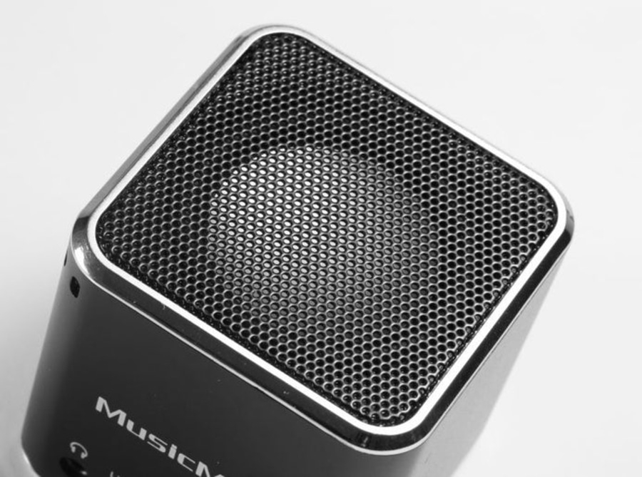Nahaufnahme eines schwarzen Lautsprechers mit Metallgitter und dem Wort MusicM
