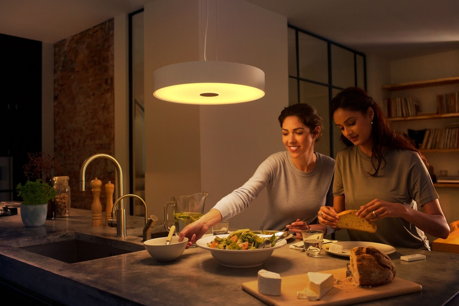 Zwei Frauen essen gemeinsam in einer Küche, Salat und Brot auf dem Tisch.