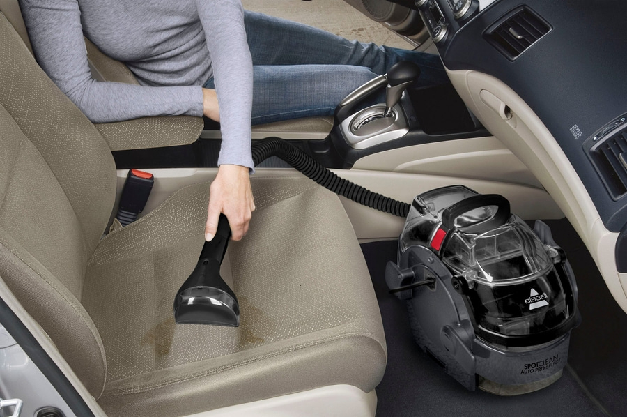 Ein BISSELL SpotClean Auto Pro Select reinigt einen schmutzigen Autositz.