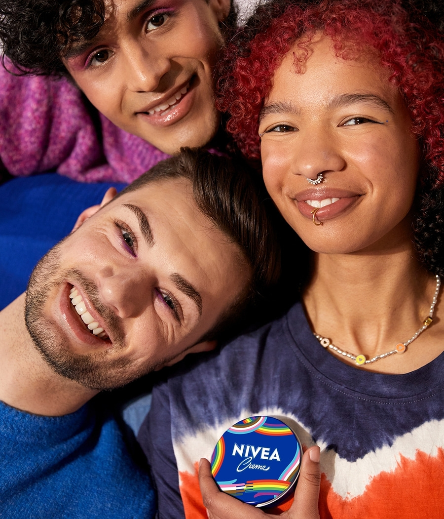Drei lächelnde Menschen halten eine Nivea Creme-Dose mit Regenbogen-Design