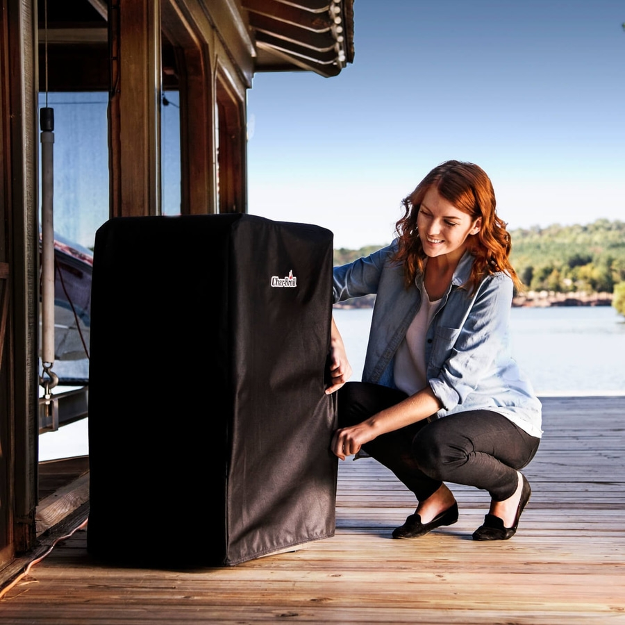 Frau deckt Grill ab. Schwarze Abdeckung. Holzterrasse. See im Hintergrund. Char-Broil.