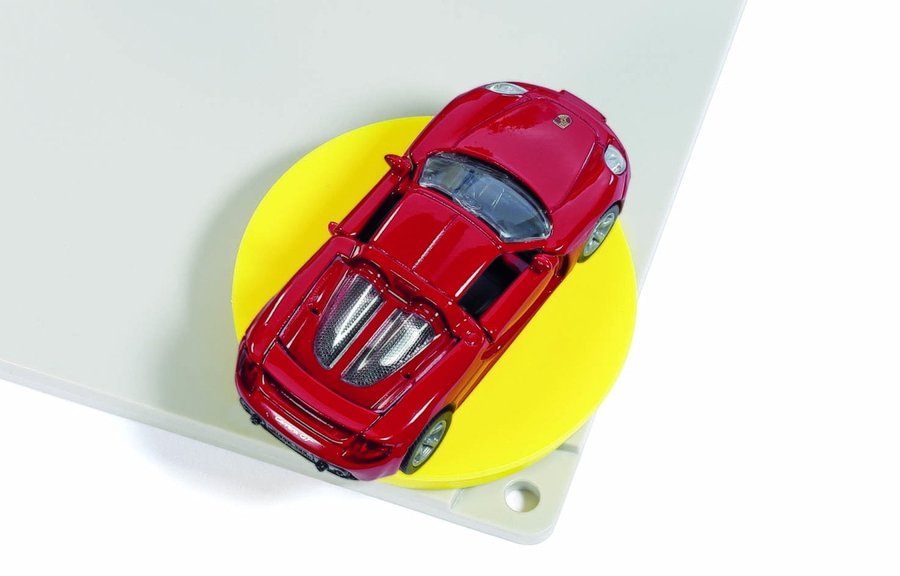 Rotes Spielzeugauto auf gelbem Kreis und weißem Hintergrund. Spielzeugauto-Modell