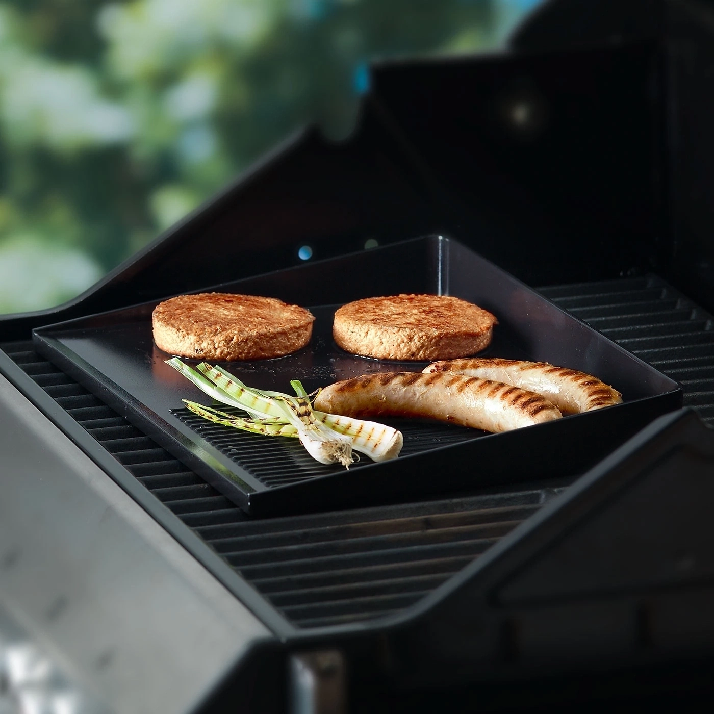 Grill mit Burgern, Würstchen und Zwiebeln. Essen wird gegrillt.