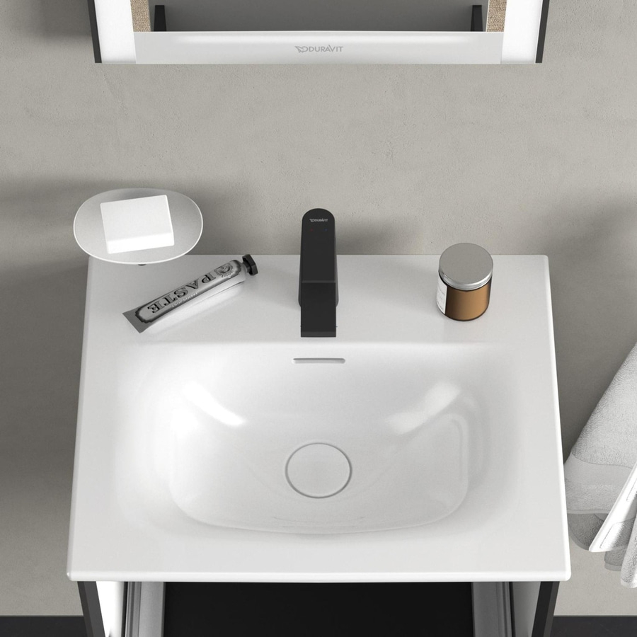 Waschbecken mit Zahnpasta, Seife, Wasserhahn und einem Glasbehälter