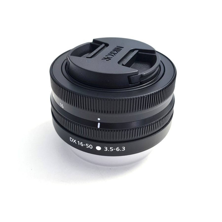 Ein schwarzes NIKKOR DX 16-50mm Objektiv mit Objektivdeckel