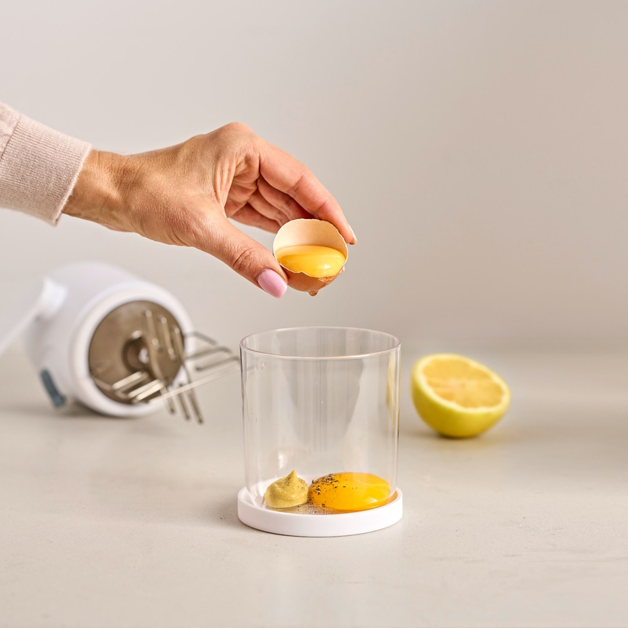 Hand trennt Eigelb, Zitrone, Senf, Mixer, Zutaten für Mayonnaise