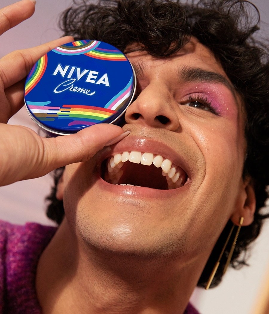 Person mit Regenbogen-Nivea-Dose vor dem Auge