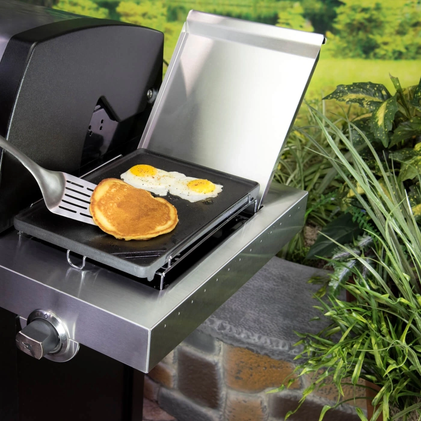 Ein Grill mit Spiegelei und Pfannkuchen, mit Spatel, im Freien.