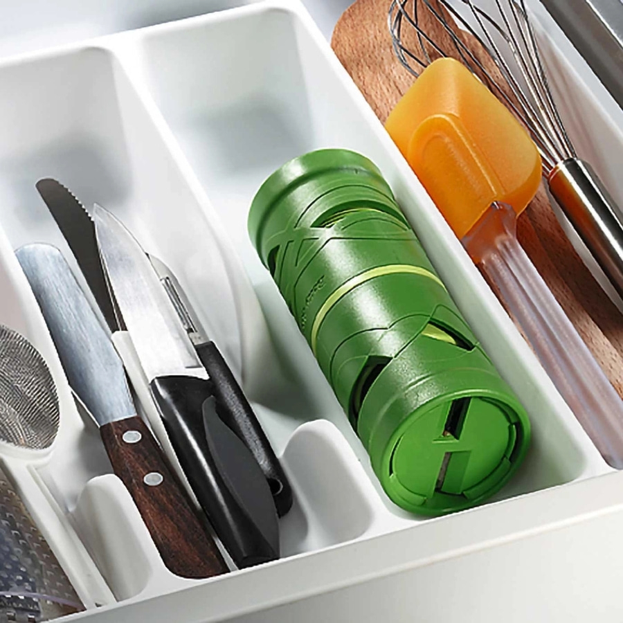 Küchenutensilien in einer Schublade: Messer, Schneebesen, Spatel, grüner Behälter.