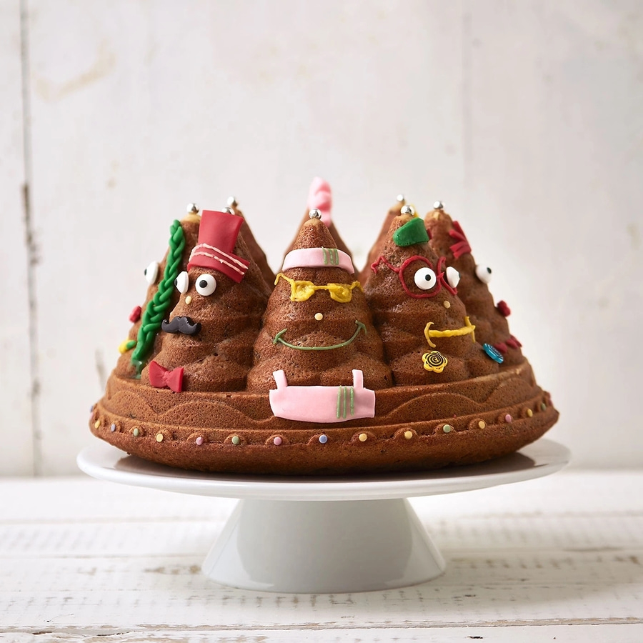 Kuchen mit Gesichtern, auf einer weißen Kuchenplatte, vor weißem Hintergrund.