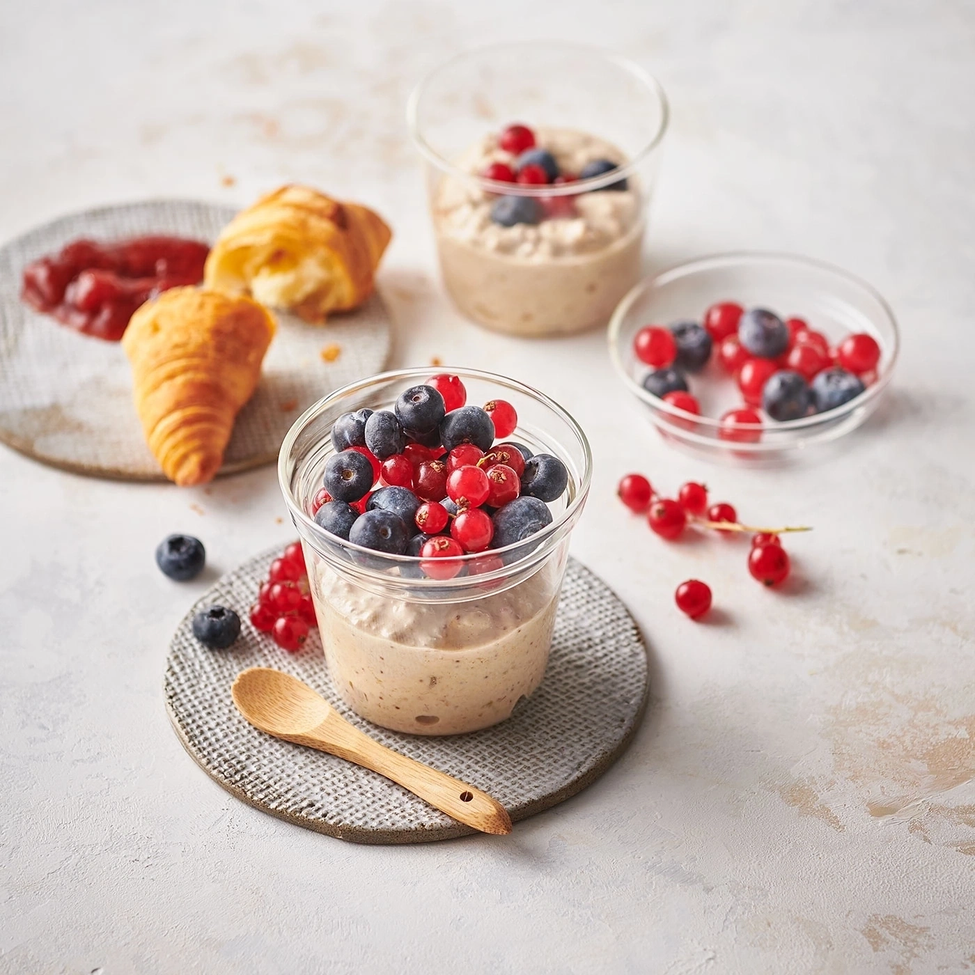 Frühstück mit Beeren, Croissant und Marmelade in Gläsern