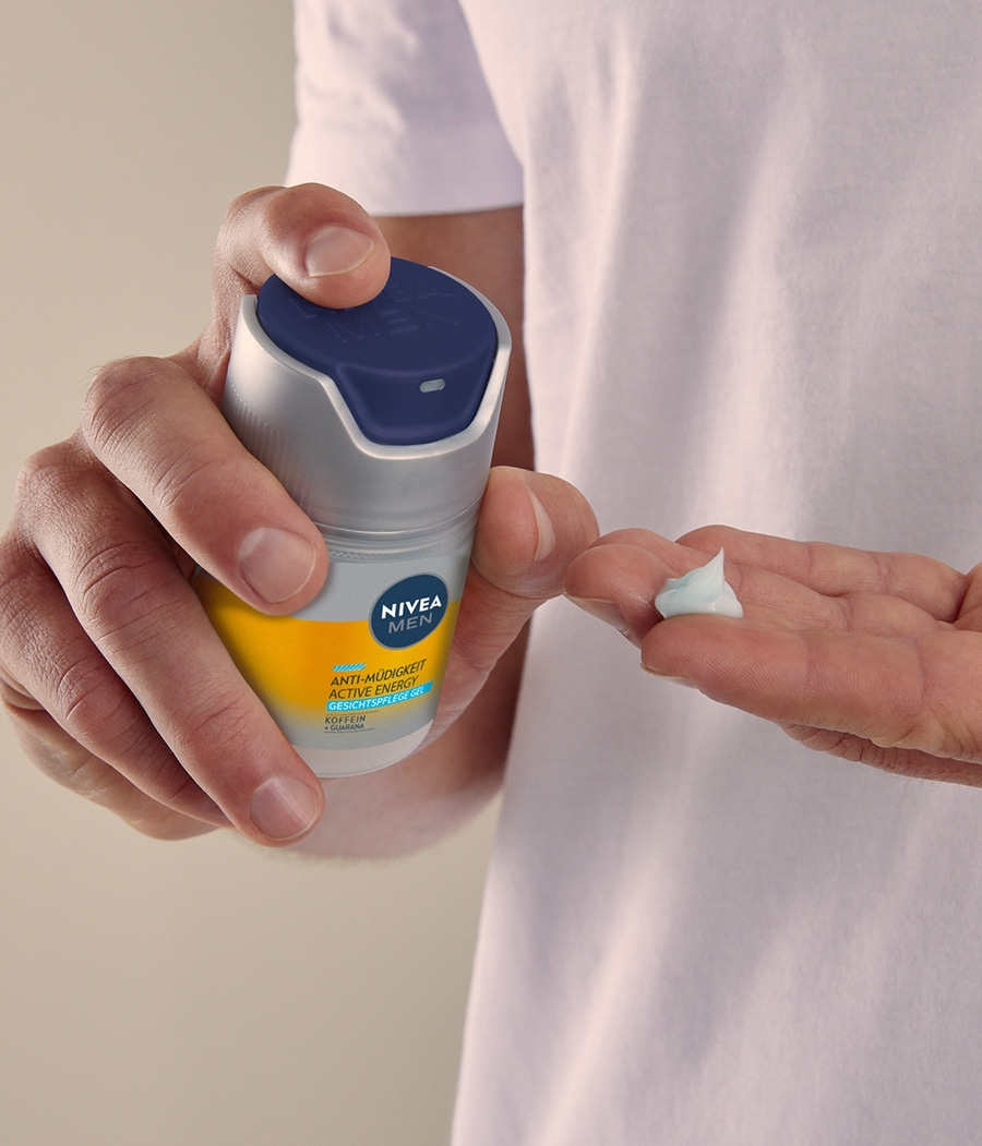 Mann hält Nivea Men Produkt und Creme in der Hand. Hautpflege.