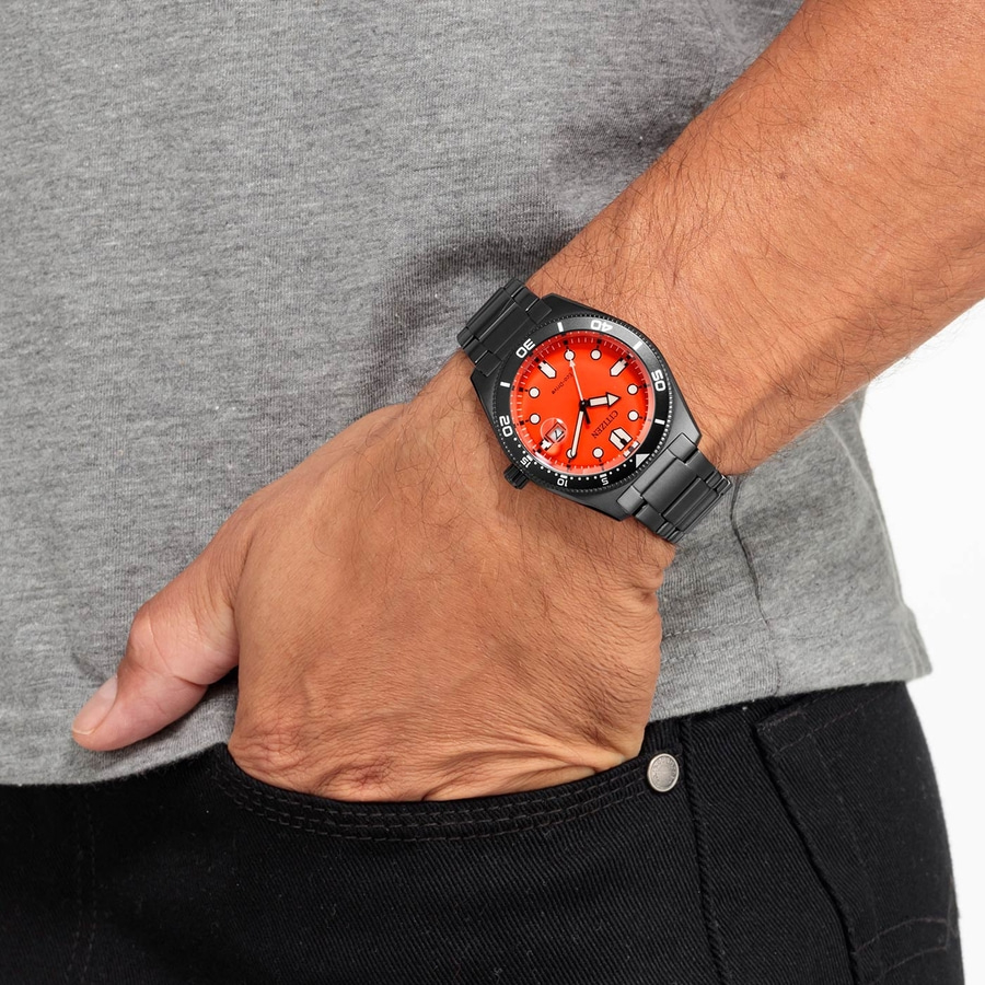 Mann trägt schwarze Uhr mit rotem Zifferblatt und graues T-Shirt und schwarze Hose.