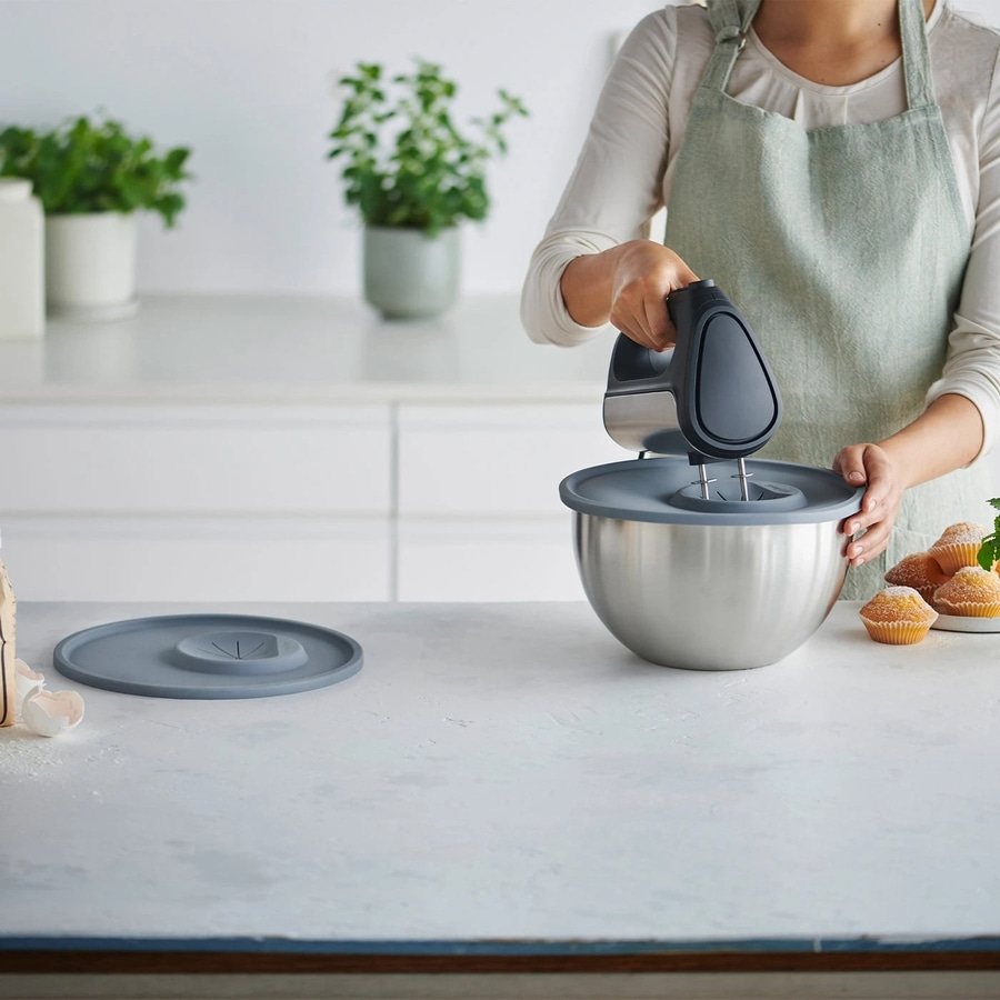 Person rührt mit Mixer in Schüssel, daneben Muffins und Zutaten.