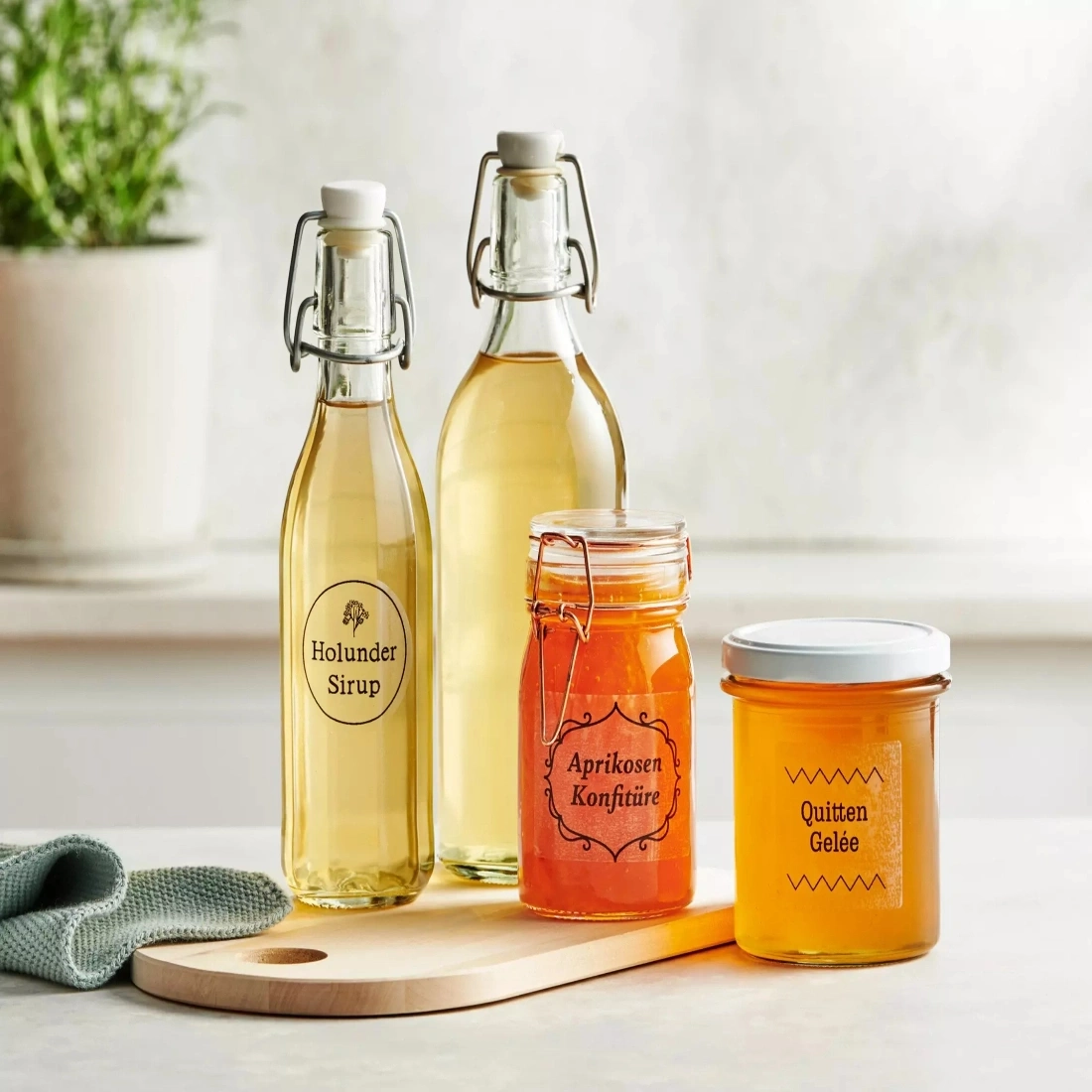 Drei Gläser mit Sirup, Marmelade und Gelee auf einem Holzbrett.