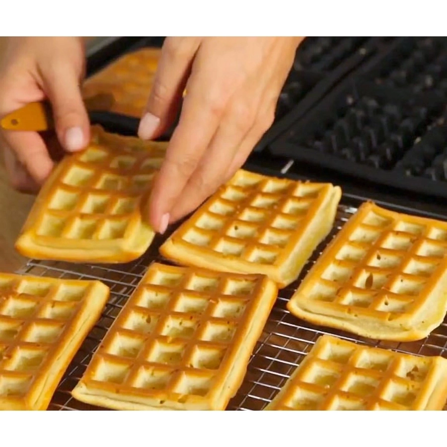 Frisch gebackene Waffeln werden aus dem Waffeleisen genommen und auf einem Rost platziert.
