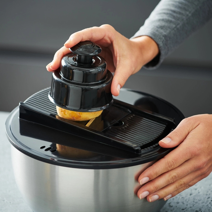 Person schneidet Kartoffel mit einem Küchengerät in einer Schüssel.