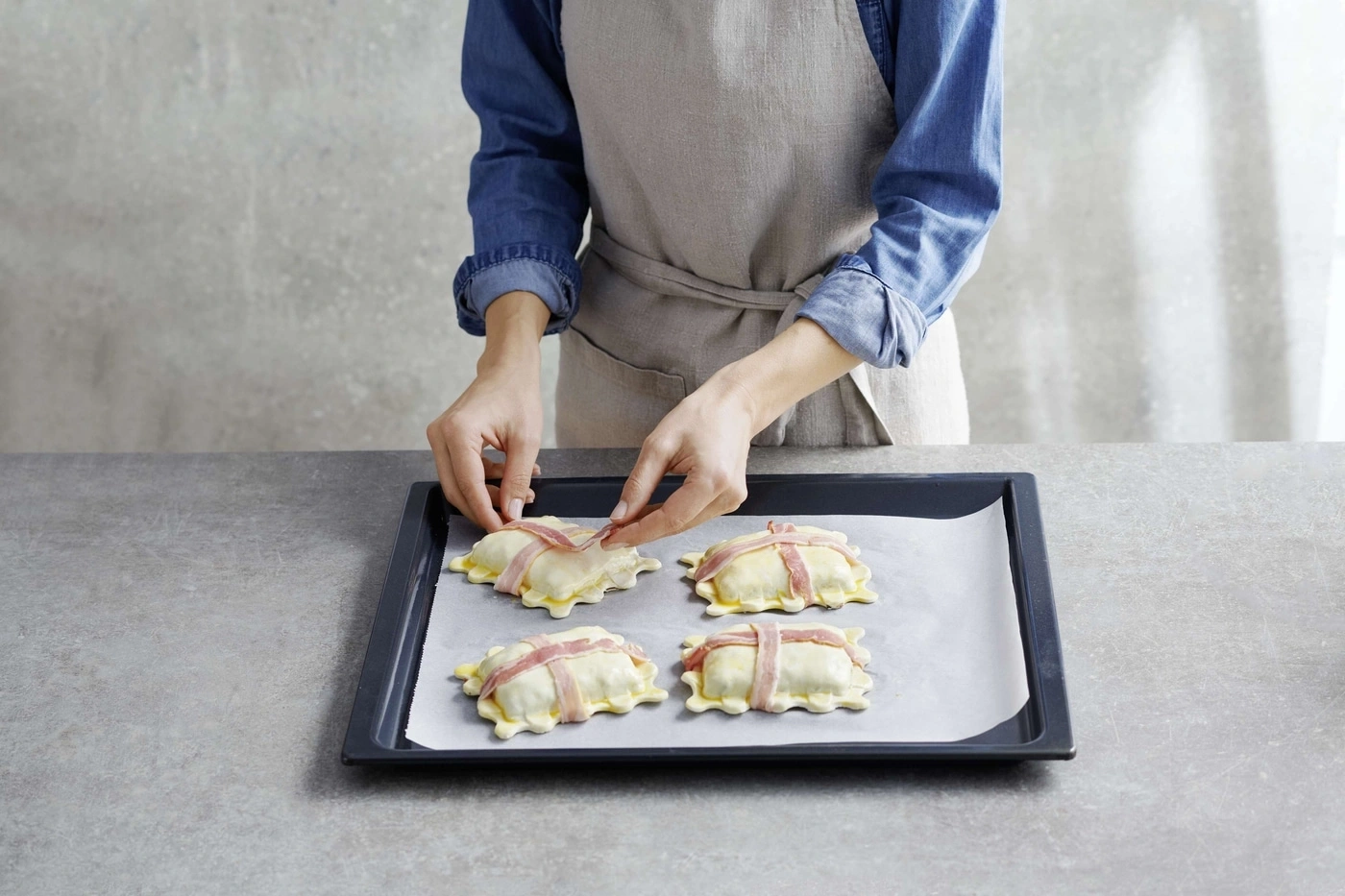 Person legt Speck auf Gebäck auf einem Backblech. Küche, Kochen, Essen.