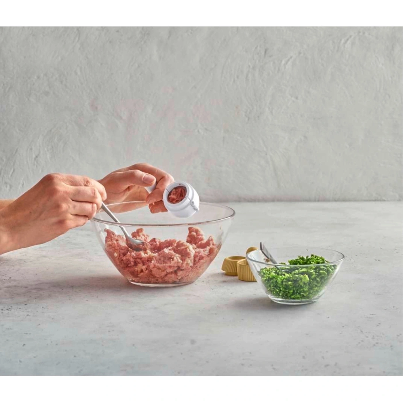 Person bereitet Essen zu, Hackfleisch, Kräuter, Schüssel, Löffel, Küchenutensilien