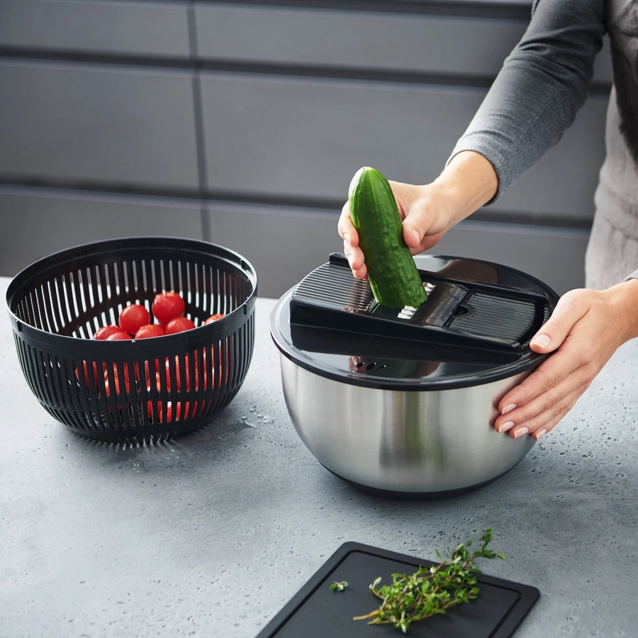Person schneidet Gurke mit Küchengerät, daneben Tomaten in einem Sieb.