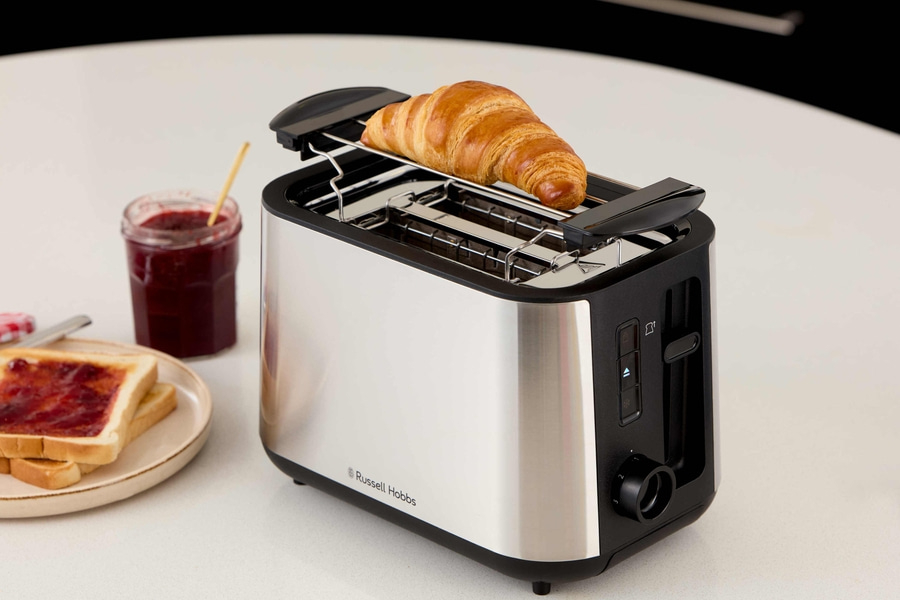 Ein Toaster mit Croissant, Marmelade und Toast auf einem Tisch.