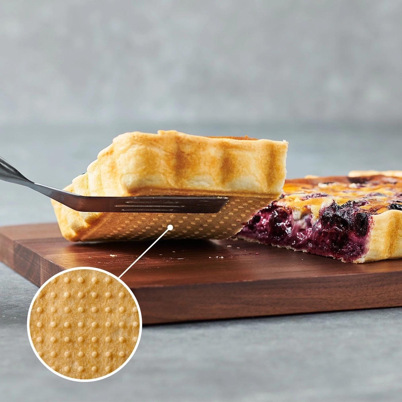 Blaubeerkuchen wird mit einem Spatel aus Holzbrett herausgehoben, Nahaufnahme