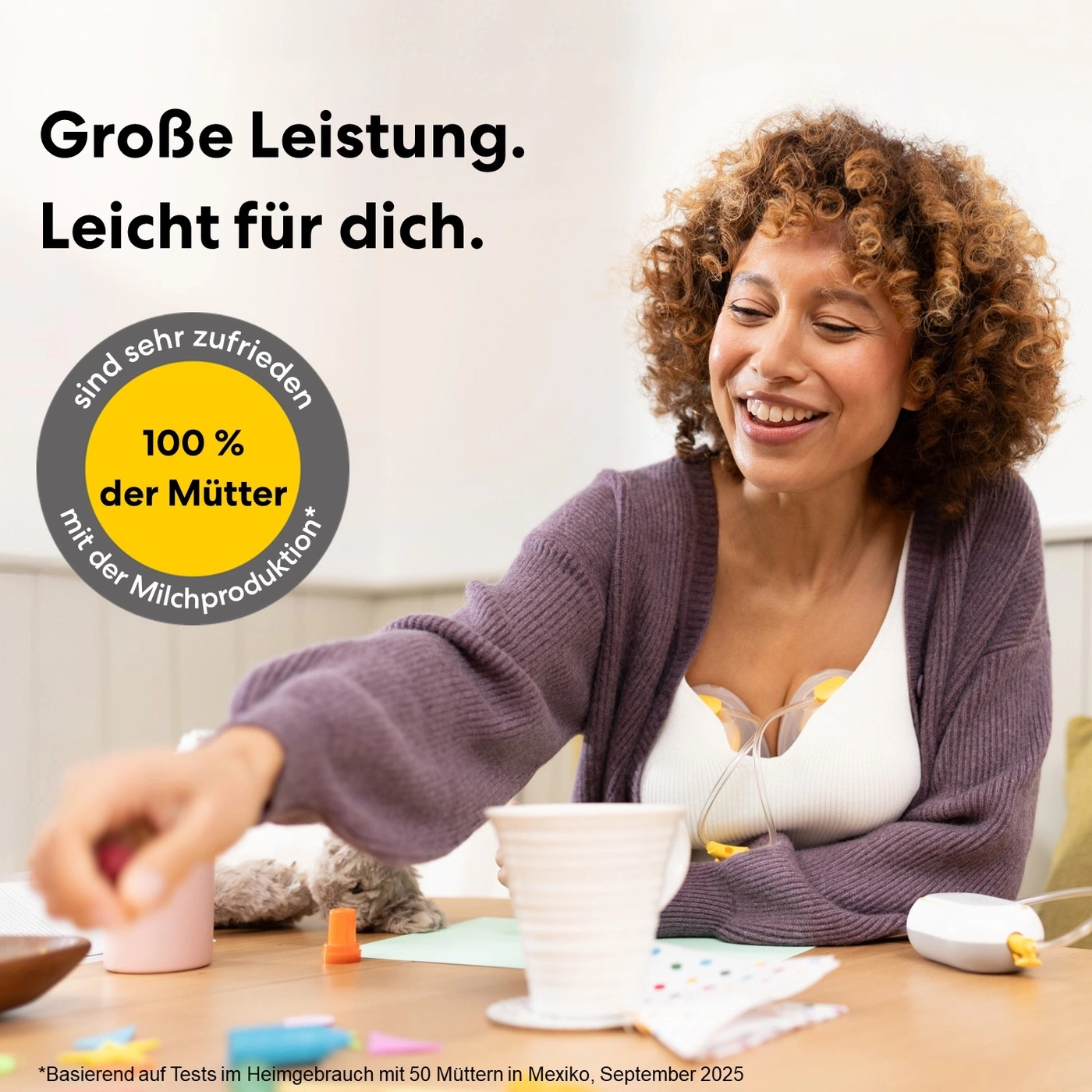 Frau lächelt, während sie mit einer Milchpumpe dasitzt, 100% der Mütter sind zufrieden.