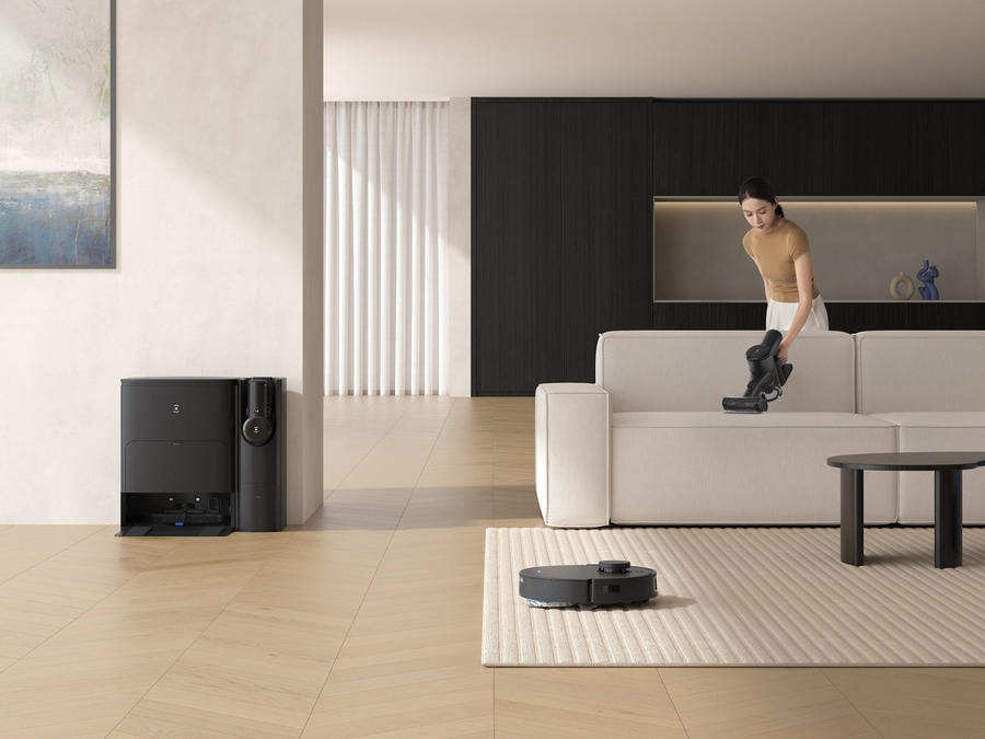 Frau saugt Sofa mit Staubsauger, Roboter-Staubsauger, modernes Wohnzimmer