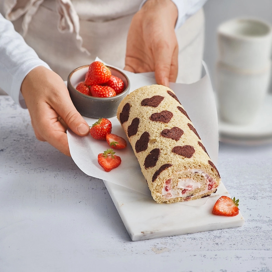 Erdbeer-Biskuitrolle mit Schokoladenflecken, serviert mit Erdbeeren.