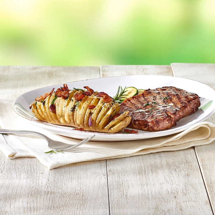 Teller mit Steak, Kartoffel und Gemüse auf einem Holztisch